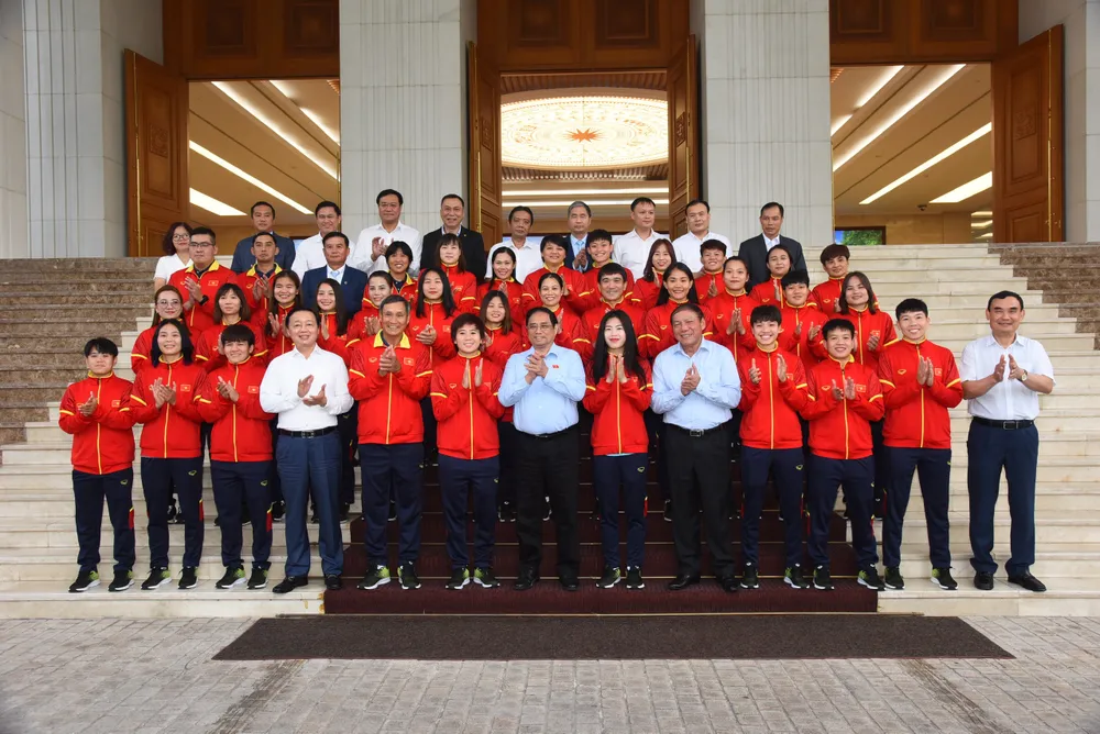 Thủ tướng Phạm Minh Chính chụp ảnh chung với Ban huấn luyện và cầu thủ đội tuyển bóng đá nữ Việt Nam. Ảnh: HẢI HÀ/nhandan.vn