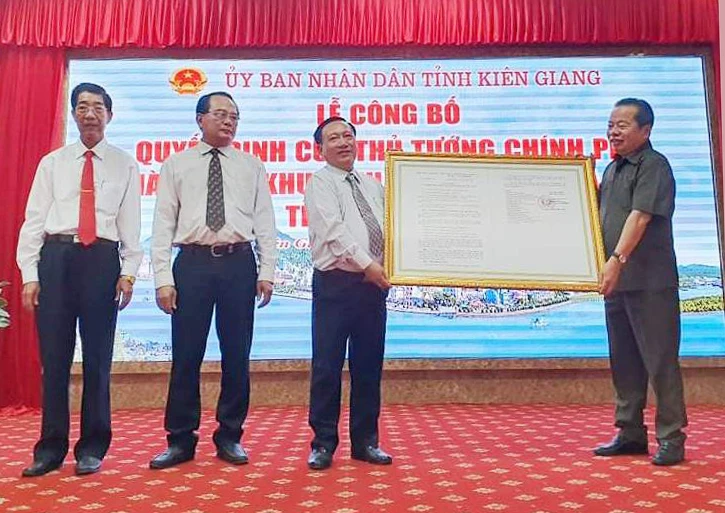 Ông Mai Văn Huỳnh (bên phải), Phó Bí thư Thường trực, Chủ tịch HĐND tỉnh Kiên Giang, thừa uỷ quyền của Thủ tướng Chính phủ trao quyết định thành lập Khu kinh tế cửa khẩu Hà Tiên. Ảnh: KHÁNH THÙY