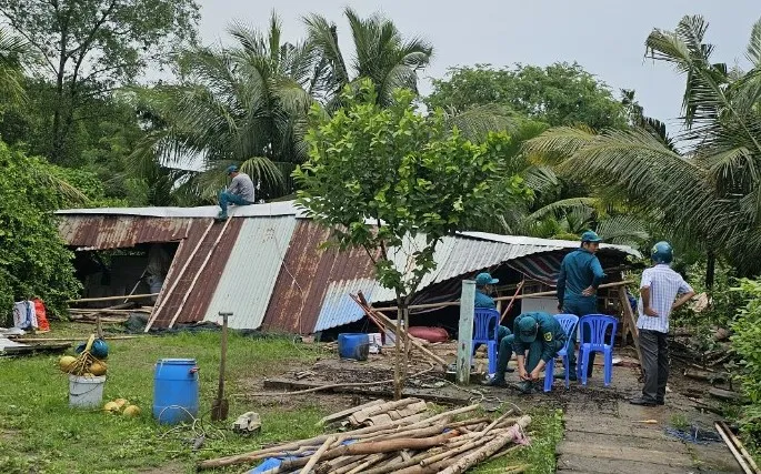 Lực lượng dân quân giúp dân khắc phục thiệt hại do lốc xoáy gây ra. Ảnh: THANH TOÀN Dong loc thiet hai 1.jpg