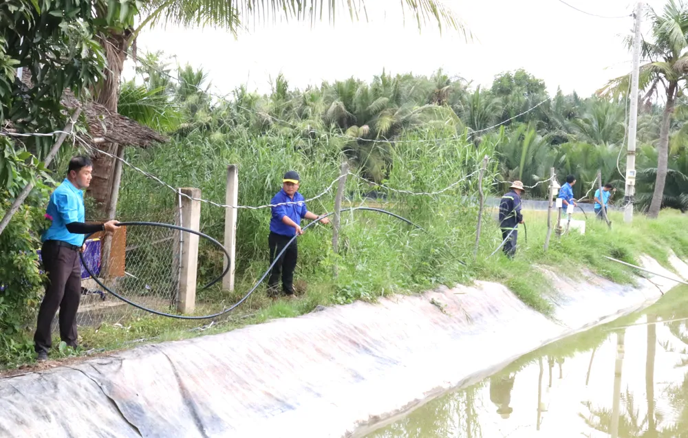 Nhân viên Xí nghiệp Cấp nước Cần Giờ kéo đường ống để gắn đồng hồ nước đến nhà người dân cù lao Mỹ Khánh XHH 8E.jpg