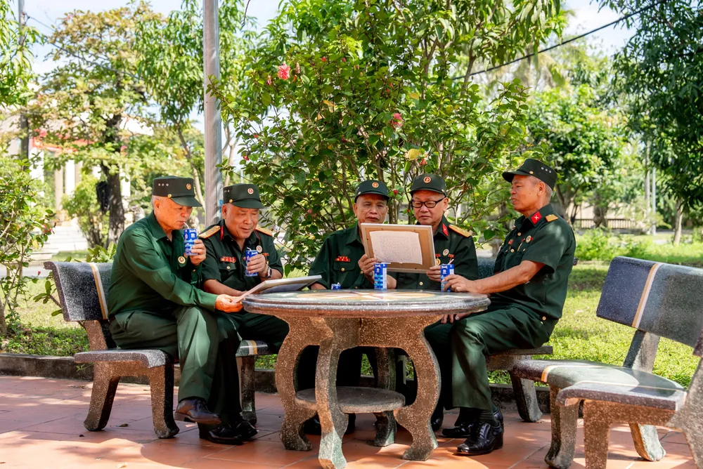 Các bác cựu chiến binh chăm chú đọc những dòng chữ nhỏ, được các em gửi kèm trong mỗi bức tranh. Ảnh: DUY CƯỜNG ANH 4A.jpg