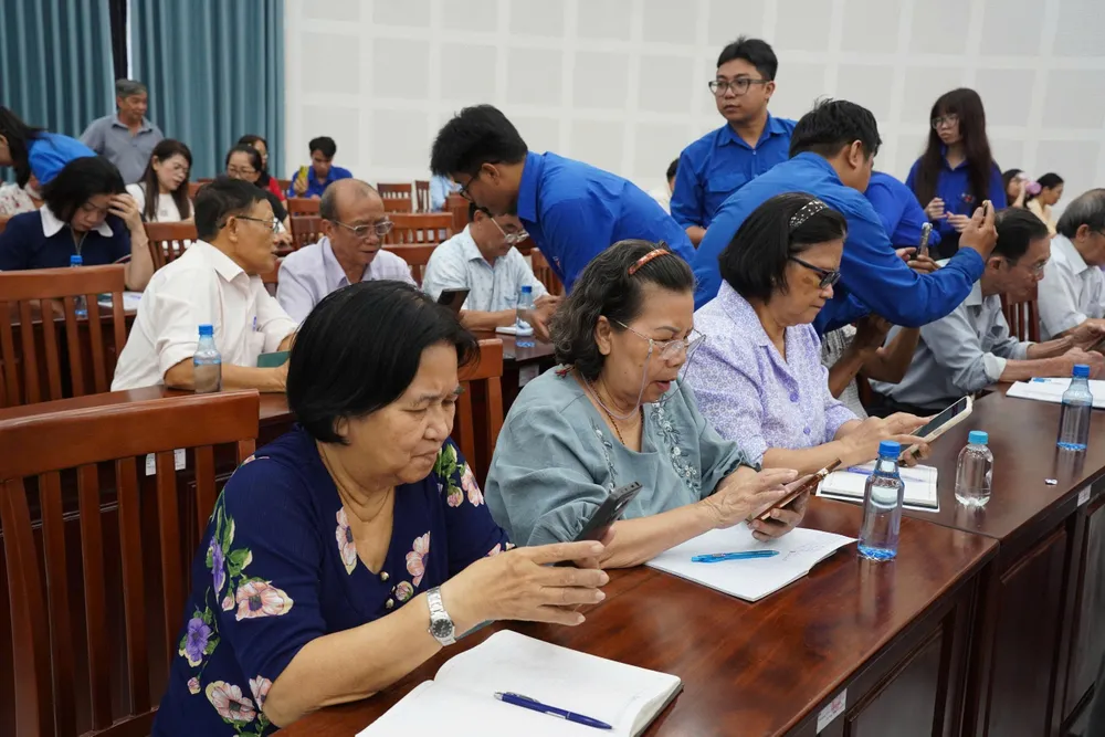 Cán bộ, đoàn viên thanh niên hướng dẫn người dân sử dụng các phần mềm trên điện thoại thông minh. Ảnh: TIỂU NGHĨA z6949163667061_6e9131969fddd6796a7b0f568dc06af5.jpg