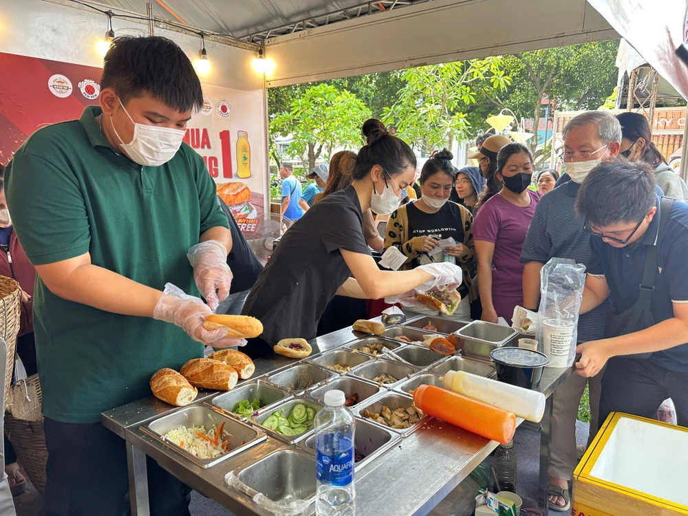 Người dân xếp hàng mua và thưởng thức bánh mì trong chiều và tối 21-3, tại công viên Lê Văn Tám