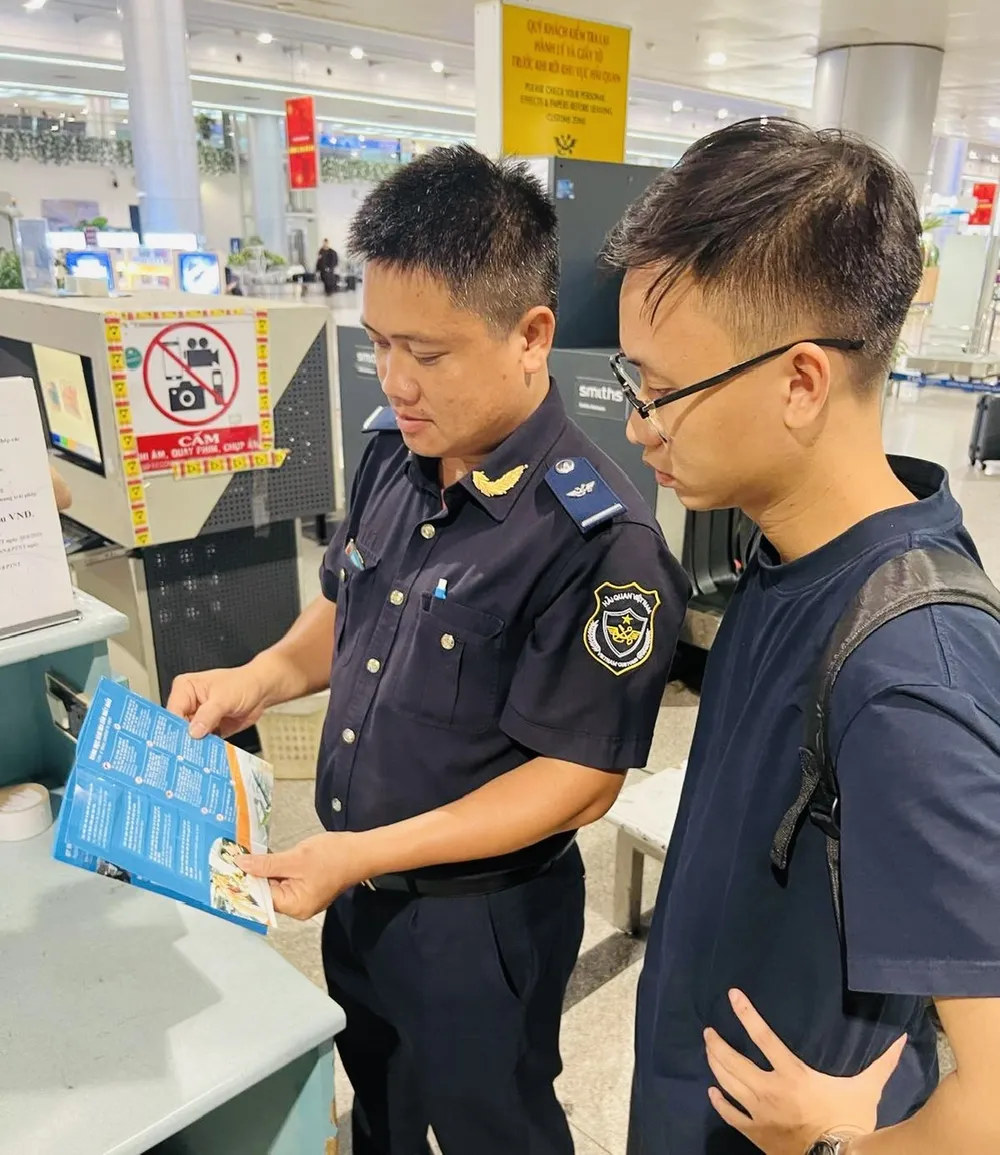Tan Son Nhat airport customs officers disseminate regulations on carry-on baggage to tourists. Công chức hải quan tuyên truyền đến du khách....jpg