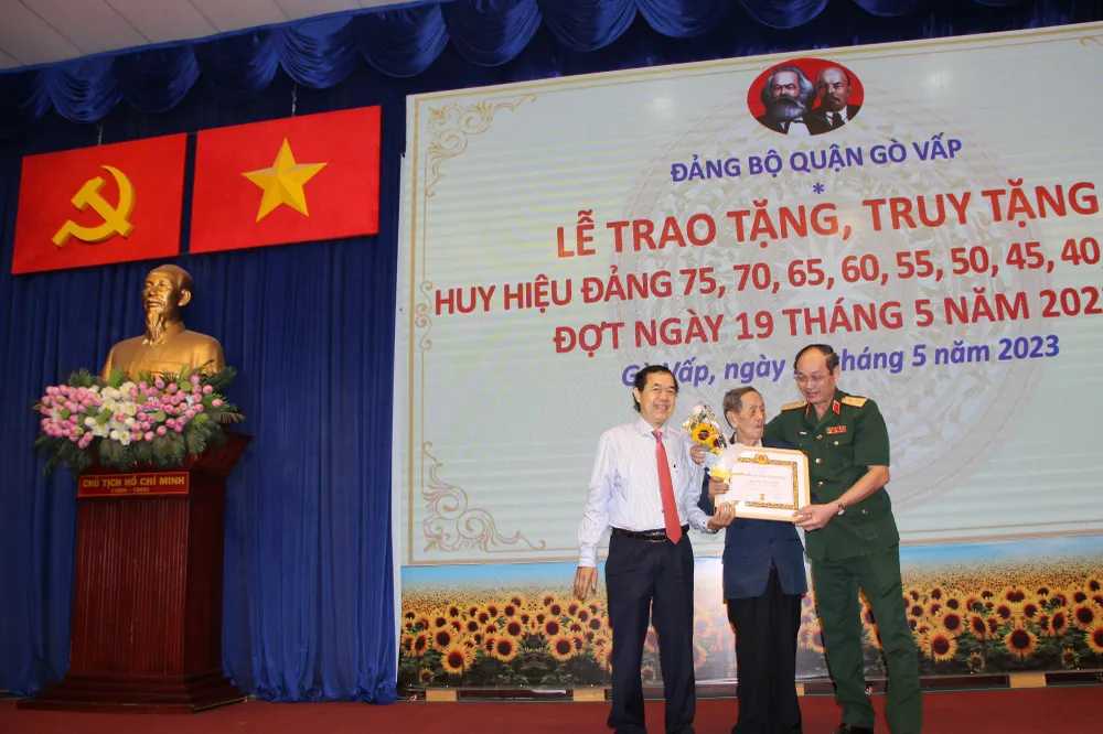 Trung tướng Nguyễn Văn Nam và đồng chí Sử Ngọc Anh, Bí thư Quận ủy quận Gò Vấp trao Huy hiệu 65 năm tuổi Đảng đến đảng viên Trần Xuân Liêm (Đảng bộ phường 17).