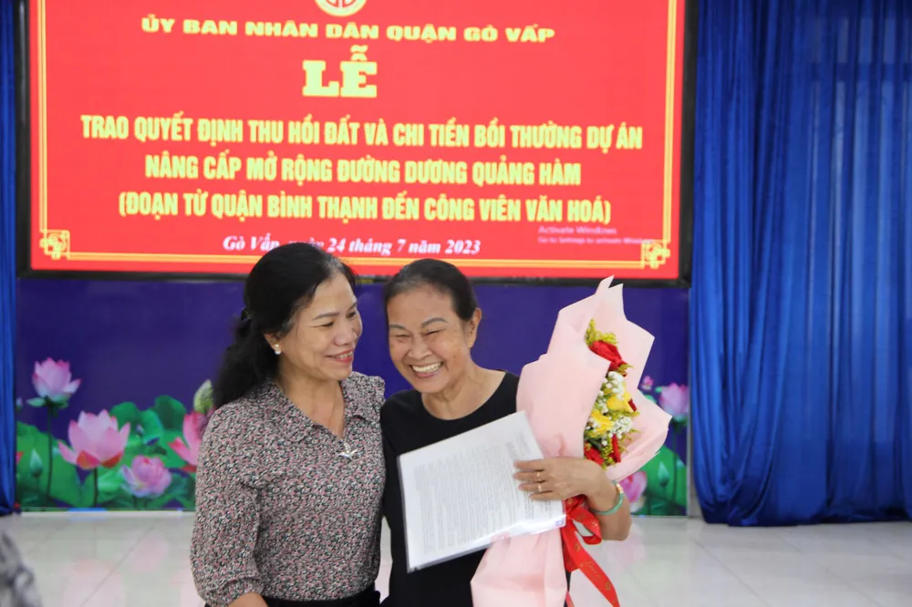 Bà Đậu Thị Kim Lài (bên phải) vui mừng nhận quyết định thu hồi đất và chi trả tiền bồi thường