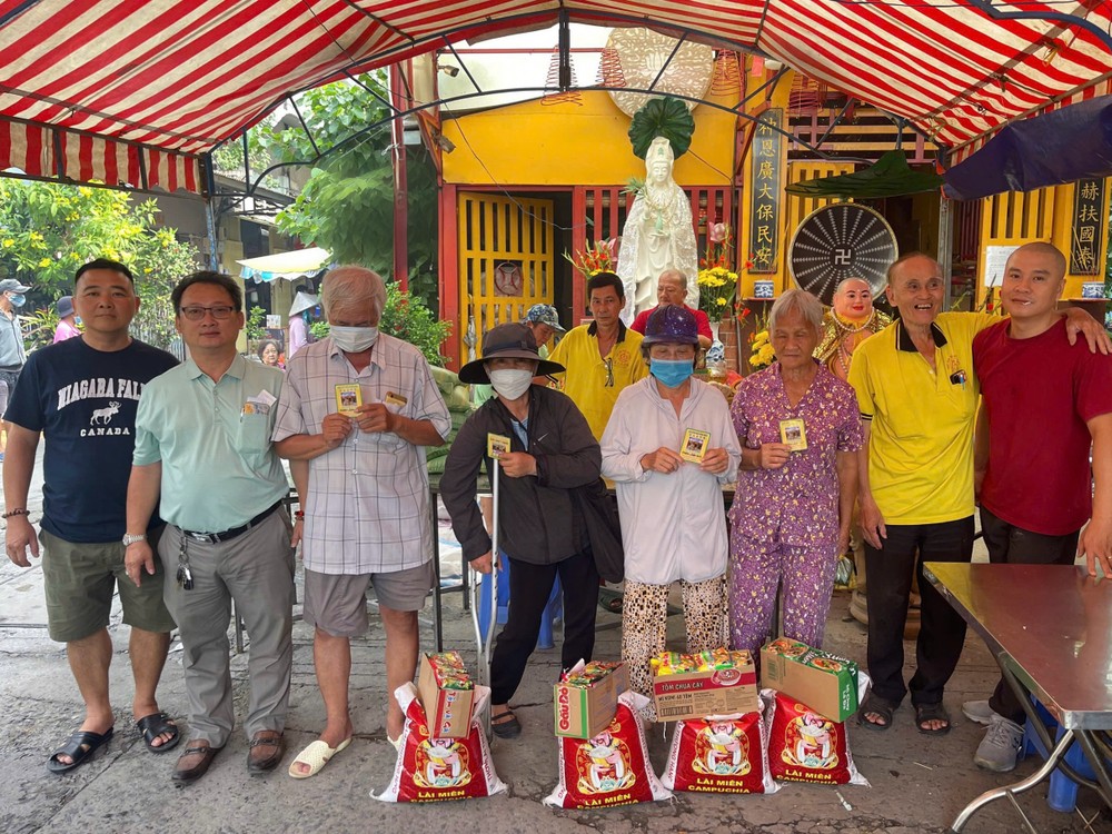 富山五行庙慈善组组长邹国荣（左二）向贫困者派发赈济品。