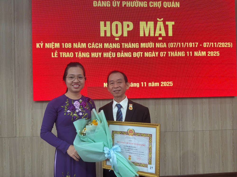 胡志明市左关坊党委常务副书记胡氏竹江祝贺华人退休干部梁鸿德荣获30年党龄纪念章。