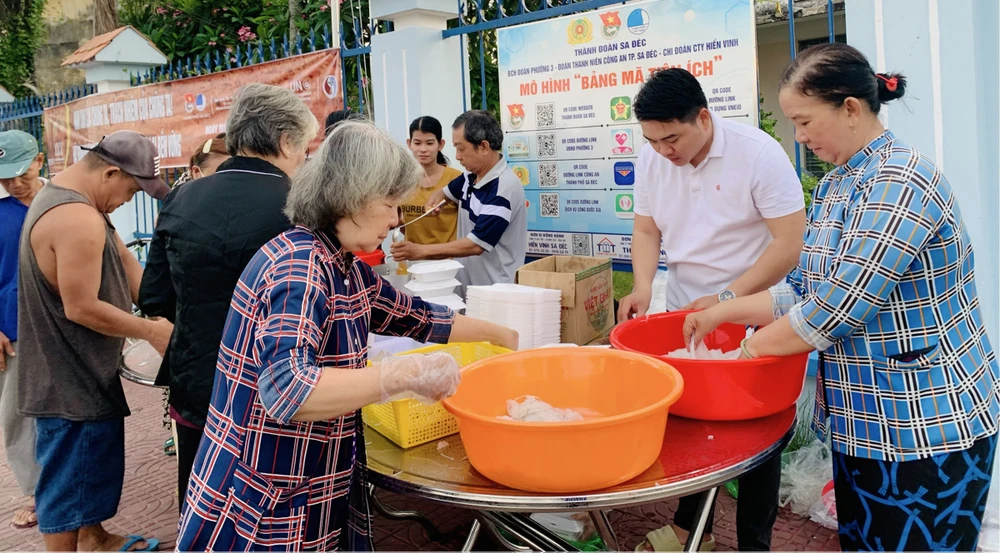 Anh Ngô Văn Quí (thứ 2 từ phải sang) chuẩn bị những suất ăn 0 đồng trao đến người nghèo