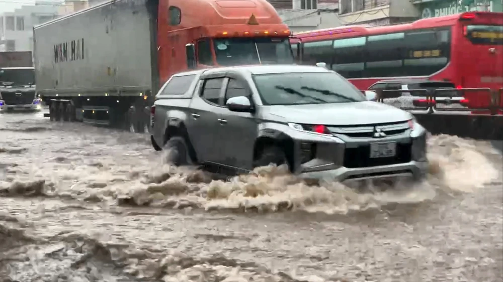 Phương tiện vượt qua điểm ngập lụt nặng ở QL1, đoạn qua thị trấn Bình Dương vào chiều 3-6-2024. Ảnh: XUÂN HUYÊN