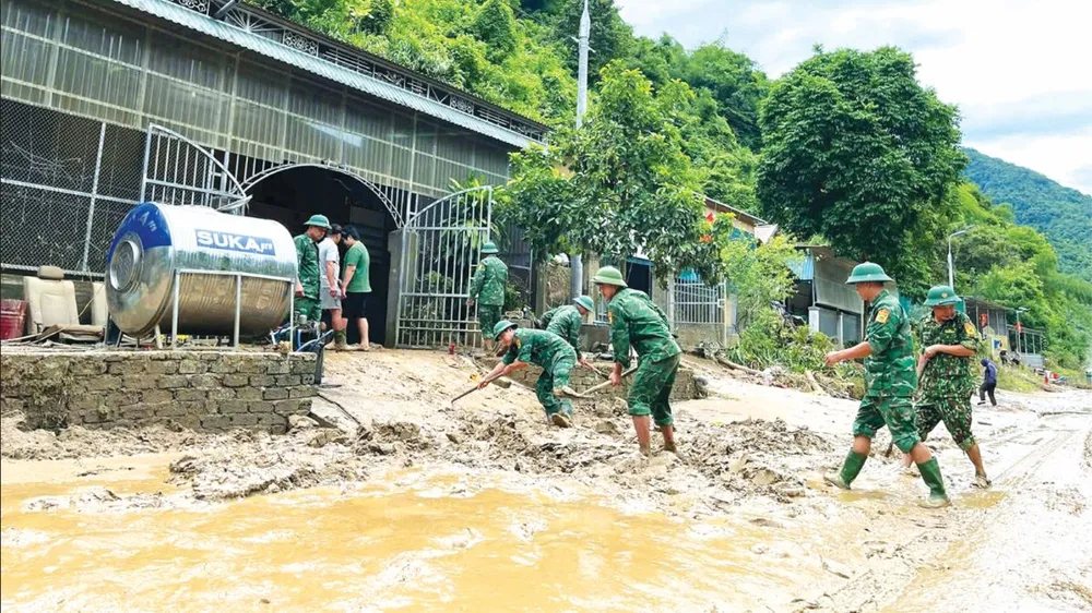 Cán bộ, chiến sĩ Đồn Biên phòng Nậm Càn (tỉnh Nghệ An) hỗ trợ bà con khắc phục hậu quả lũ lụt. Ảnh: DƯƠNG QUANG Screenshot 2025-07-26 050409.png