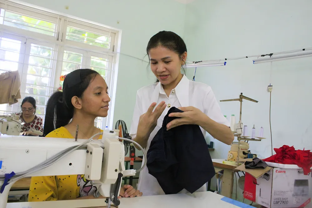 Cô giáo trợ giảng Nguyễn Thị Kim Ngân đang dùng ngôn ngữ ký hiệu hướng dẫn học sinh cách may V4b.jpg