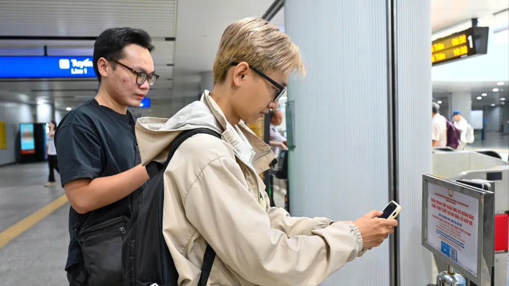 Hành khách di chuyển bằng metro ủng hộ đồng bào bị ảnh hưởng do mưa lũ thông qua các điểm bố trí QR code ủng hộ. Ảnh: MẠNH THẮNG