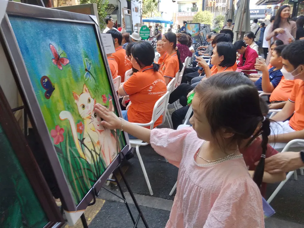 Uma criança pequena se diverte observando as pinturas na exposição. Ảnh 8.jpg