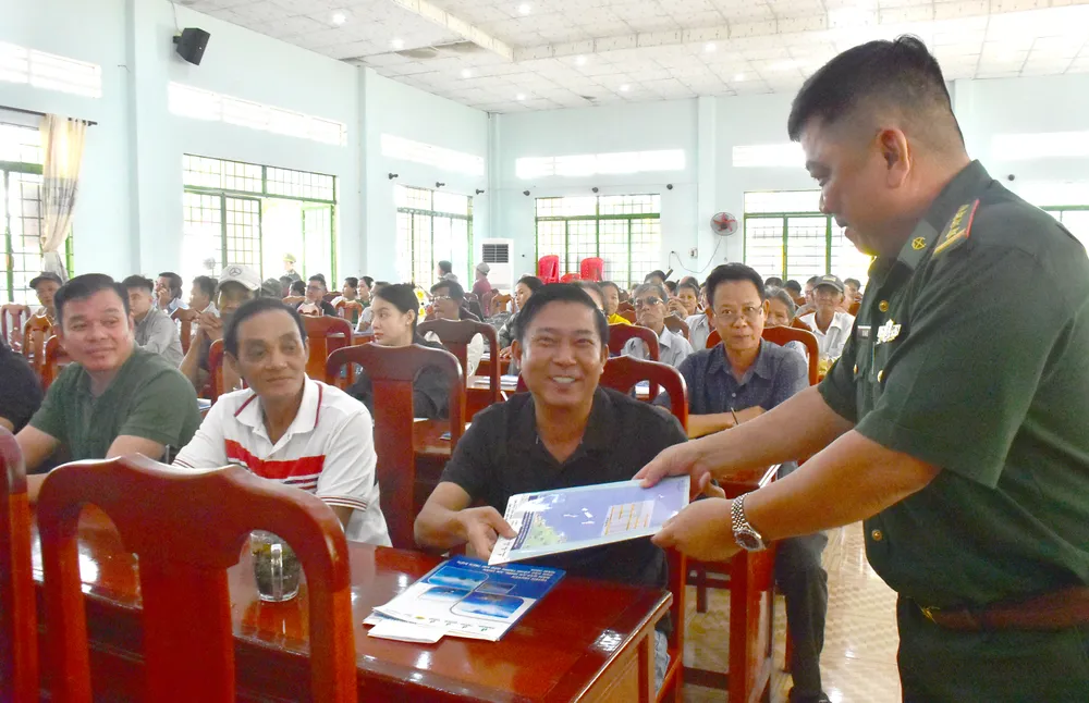 Đại diện Đồn Biên phòng Tây Yên phát tài liệu tuyên truyền đến ngư dân, chủ phương tiện. Ảnh: NAM KHÔI DSC_0466.jpg