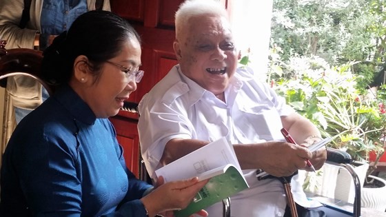 Professor Cao Minh Thi signs on a book to present to Ms. Dung  as a gift (Photo: SGGP)