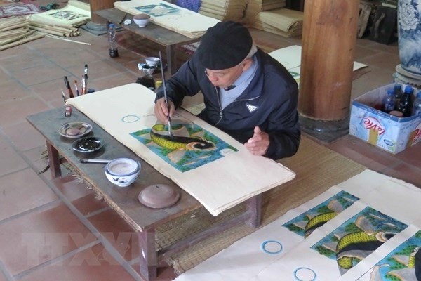 Artisan Nguyen Dang Che finishes a Dong Ho painting called Ca Chep Trong Trang (Moonlight Carp) (Photo: VNA)