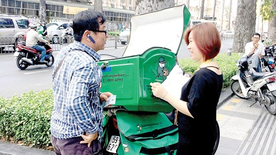 A man delivers goods to an online shopper (Photo: SGGP)