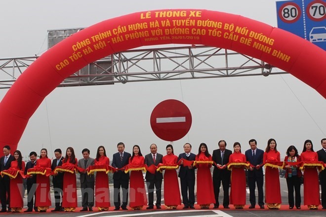 Prime Minister Nguyen Xuan Phuc (9th from right) cuts the ribbon to open Hung Ha bridge. (Photo: VNA)