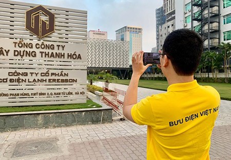 A post officer is collecting information for an address in Hanoi.