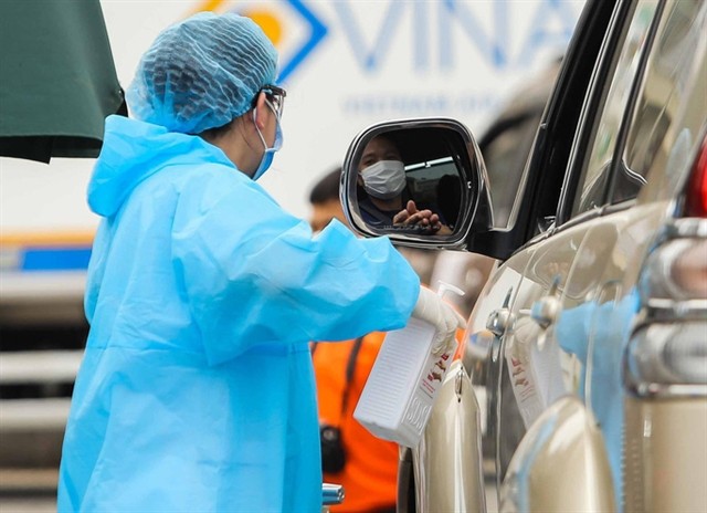 A medical worker sprays a hospital visitor with sanitiser. — Photo nld.com.vn