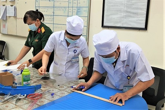 Medical workers make anti-bacterial face masks, protective plastic visors