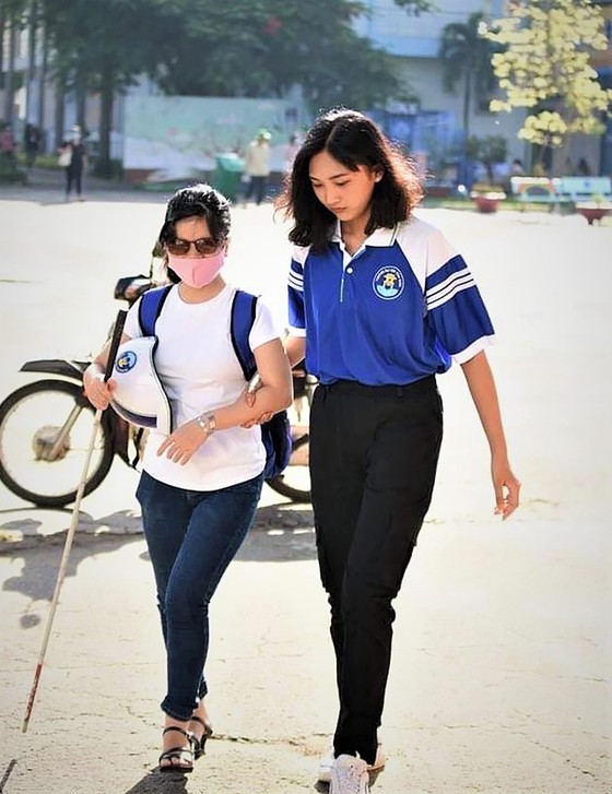 Bui Thi Hau walks in the school with the assistance of her friend (Photo: SGGP)