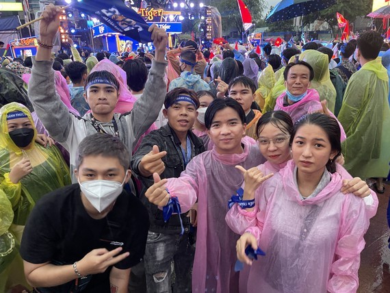Despite rain, fans in high spirit in street watching football match ảnh 1