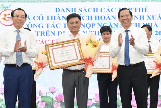 Secretary of the City Party Committee of Ho Chi Minh City Nguyen Van Nen and Chairman of the People&apos;s Committee of Ho Chi Minh City Phan Van Mai present certificates of merit to a leader of the People&apos;s Committee of Binh Chanh District for outstanding achievements in the collection and payment of the state budget (Photo: SGGP)