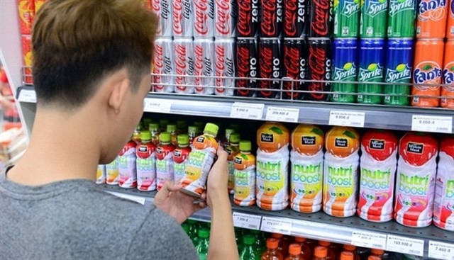 A man buys a sugary drink. A potential increase in taxes aimed at sugary beverages has aroused mixed responses. — Photo vnbusiness.vn