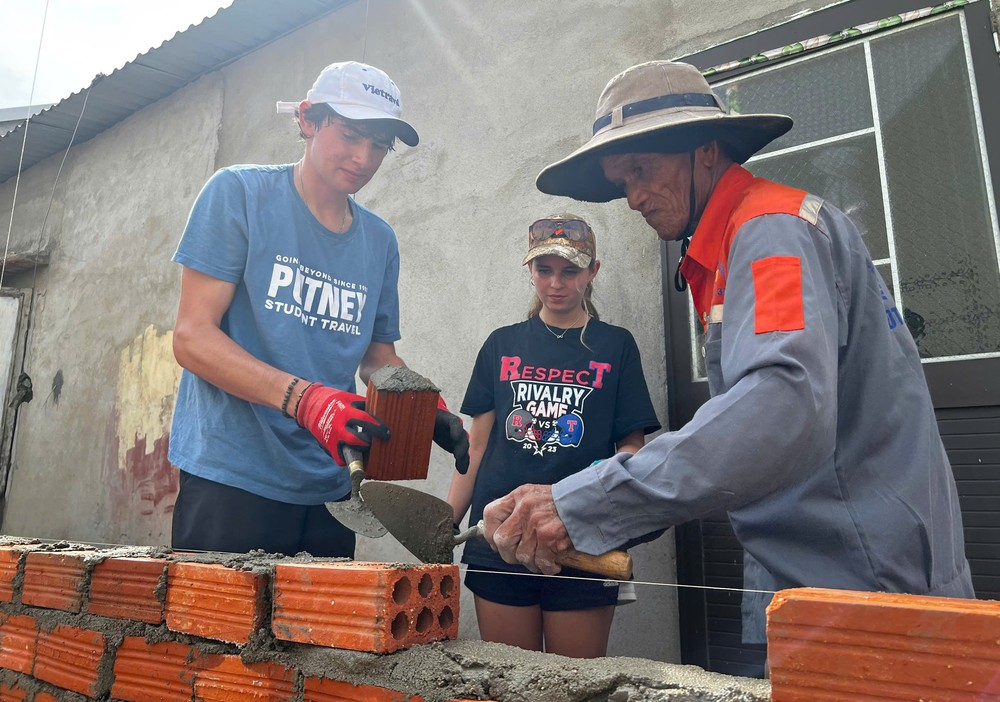 A bricklayer from Van Tuong Commune is teaching American students how to align bricks when building a wall. hoc-sinh-my-27-3932-9467.jpg.jpg