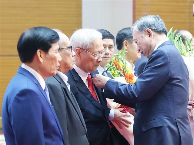 Party General Secretary To Lam presents the badges marking 80, 75, 60, 55, 50, 45, and 40-year Party membership to the veteran revolutionaries at the meeting. (Photo: VNA) lam.jpg