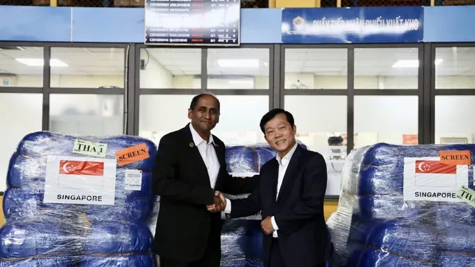 A representative from the Singapore Embassy in Vietnam presents aid to the people of Tuyen Quang Province through representatives of the Ministry of Agriculture and Environment of Vietnam. singapoer.jpg