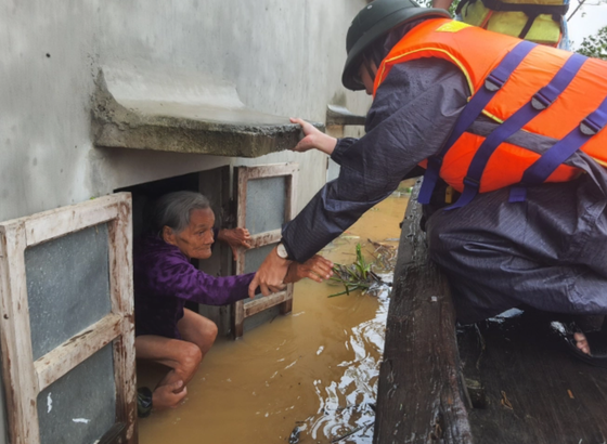 A rescue worker take an old woman out from her flooded house in Quang Binh Province (Photo: SGGP)