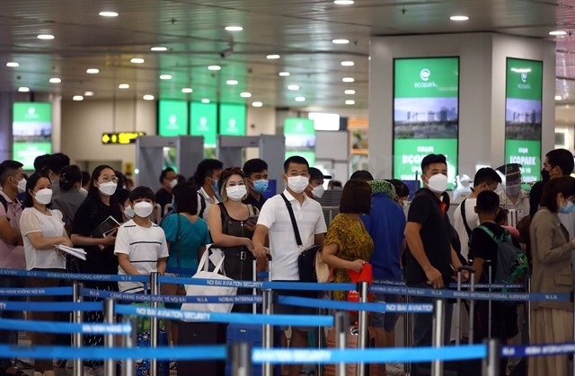 Passengers waiting in line to board a plane at Noi Bai International Airport. Passengers waiting in line to board a plane at Noi Bai International Airport.