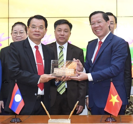 Chairman of the Ho Chi Minh City People’s Committee Phan Van Mai offers a souvenir to Secretary of the Party Committee and Governor of Houaphane Province of Laos Vansay Phengsumma. (Photo: Viet Dung)