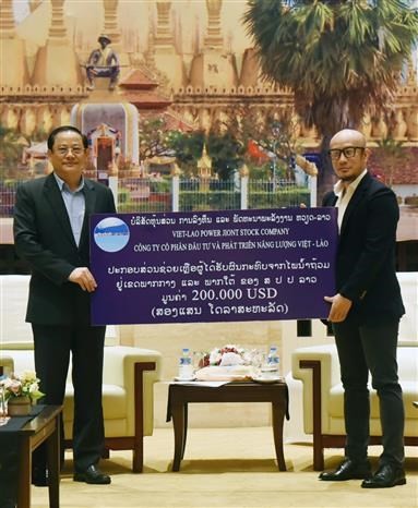 Lao Prime Minister Sonexay Siphandone (L) reeceives the donation from the Vietnam-Laos energy investment and development company (Photo: VNA)