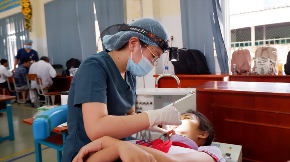 A medical staff is checking the teeth of a pupil at Can Thanh Primary School in Can Gio District. syt-raquan-rhm-5-6299.jpg (1).png