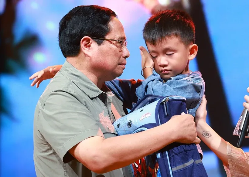 PM Pham Minh Chinh gives encouragement to a boy named Nguyen Quoc Bao, whose father and elder sister were washed away by a flood while the three were crossing a bridge in Cau Treo hamlet of Yen Thuan commune, Ham Yen district, Tuyen Quang province. (Photo: VNA) PM.jpg