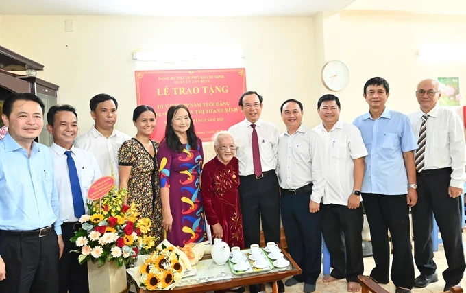 Secretary of the Ho Chi Minh City Party Committee Nguyen Van Nen and leaders of Tan Binh District congratulate Mrs. Nguyen Thi Thanh Binh as she receives the 80-year Party Membership Badge. (Photo: SGGP/ Viet Dung) 10ee08d7c69973c72a88-4773-6428.jpg