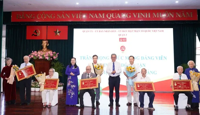 Mrs. Nguyen Thi Le and a District 3 leader congratulate to the individuals who received 65-year Party membership badges. (Photo: SGGP/ Hoang Hung) hinh-2-1825-7759.jpg