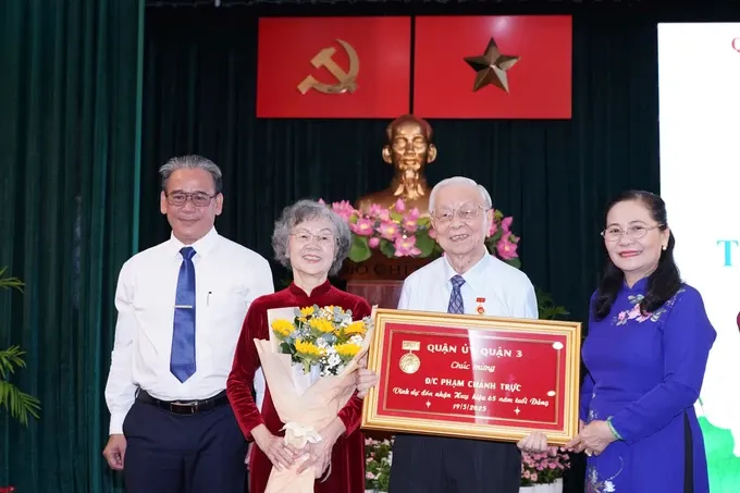 Mrs. Nguyen Thi Le presents the 65-year Party membership badge to veteran Party member of District 3 Pham Chanh Truc. (Photo: SGGP/ Hoang Hung) hinh-3-8531-342.jpg