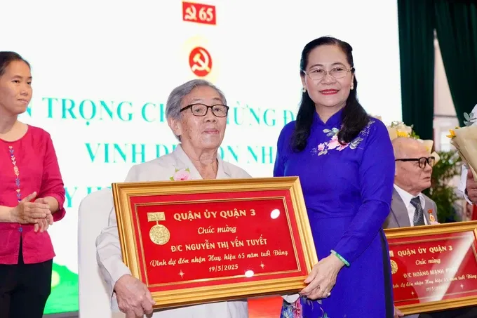 Mrs. Nguyen Thi Le presents the 65-year Party membership badge to veteran Party member of District 3 Nguyen Thi Yen Tuyet. (Photo: SGGP/ Hoang Hung) hinh-4-2004-811.jpg