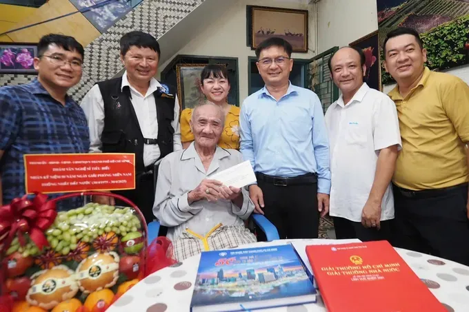 Mr.Nguyen Manh Cuong, Head of the Propaganda and Mass Mobilization Commission of the Ho Chi Minh City Party Committee, visits and presents a gift to photographer Minh Loc. (Photo: SGGP/ Hoang Hung) 1000001474-5274-5599.jpg
