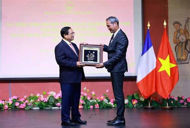 Prime Minister Pham Minh Chinh (L) presents a souvenir to a representative of the Vietnamese community in France (Photo: VNA) vna-potal-thu-tuong-va-phu-nhan-gap-go-can-bo-nhan-vien-dai-su-quan-va-cong-dong-nguoi-viet-nam-tai-phap-8084661.jpg