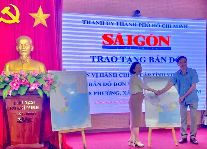 Journalist Tran Van Phong presents the provincial-level administrative map of Vietnam and the commune-level administrative map of Ho Chi Minh City to Ms. Nguyen Thu Cuc, Secretary of the Party Committee of Thu Dau Mot Ward, Ho Chi Minh City. z6783848108037-c7dab8b28e184cb91643f80b49c79909-9240-660.jpg