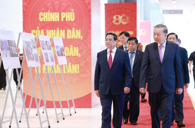 Party General Secretary To Lam (R) and PM Pham Minh Chinh, together with other delegates, visit a photo exhibition on the activities of the Government throughout history. (Photo: VNA) vna-potal-tong-bi-thu-to-lam-du-le-ky-niem-80-nam-thanh-lap-chinh-phu-8222224.jpg