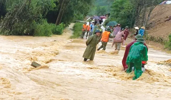 Local forces in Huong Xuan Commune, Ha Tinh Province assist residents cross a flooded spillway bridge with fast-flowing water. (Photo: SGGP/ Duong Quang) lulut-3202-5377.jpg