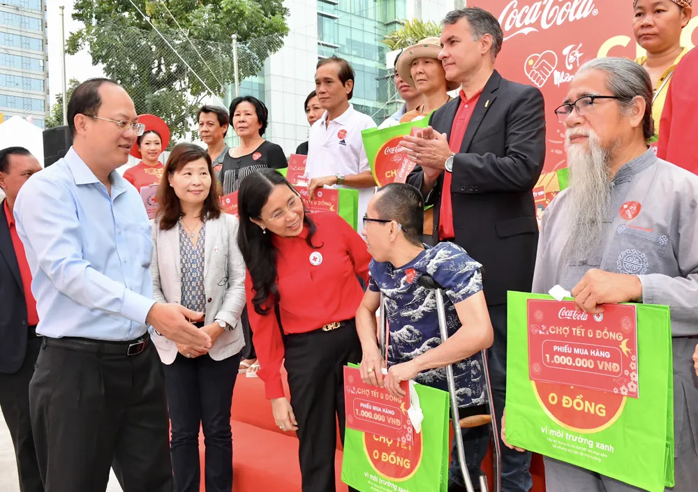Phó Chủ tịch Trung ương Hội Chữ thập đỏ Việt Nam Huỳnh Thị Xuân Lam và Phó Bí thư Thành ủy TPHCM Nguyễn Hồ Hải tặng phiếu mua hàng cho người dân. Ảnh: VIỆT DŨNG