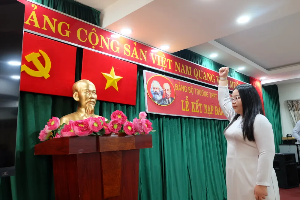 Đảng viên Nguyễn Đinh Thuỵ Ngân Giang tuyên thệ trước cờ Đảng, cờ Tổ quốc và chân dung Chủ tịch Hồ Chí Minh